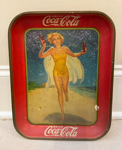 Vintage Coca-Cola tray with a woman in a yellow dress and wings holding bottles on a beach.